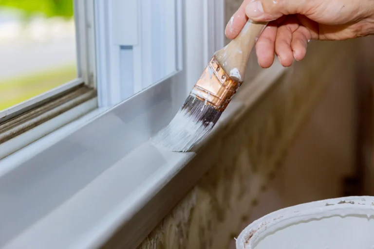 Painter hand brushing interior window trim in Chico, CA home