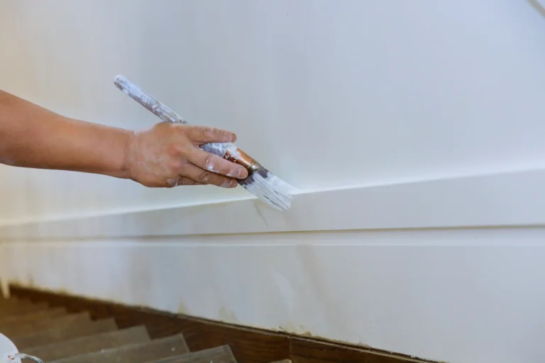 Painter applying white paint to trim with brush in Chico, CA home
