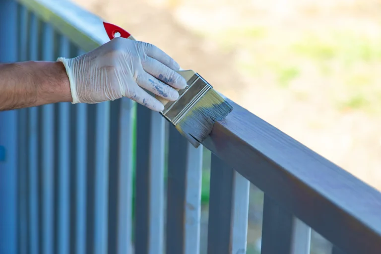 Close-up of painter brushing outdoor deck railing in Chico, CA