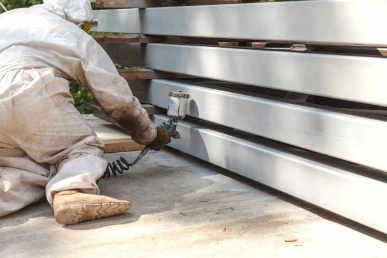 Professional painter spraying industrial beams with protective coating