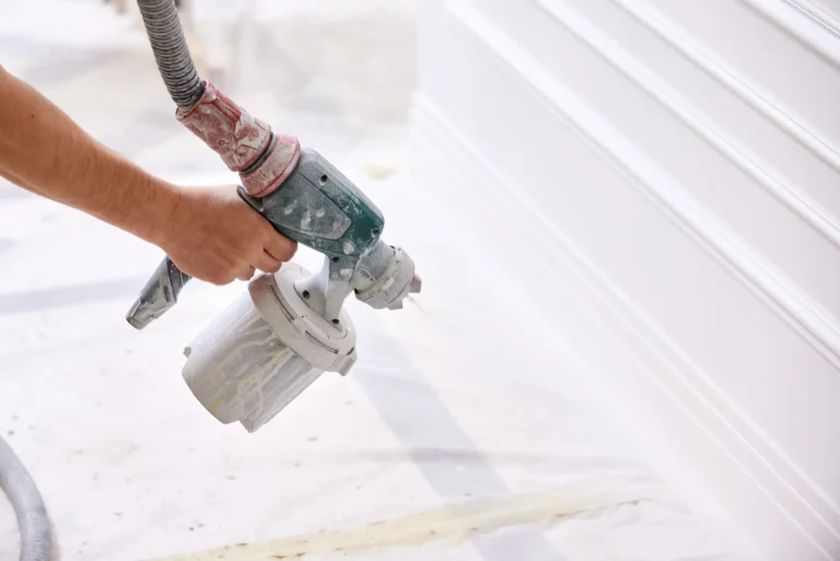 Professional painter using sprayer on baseboard trim in Chico, CA